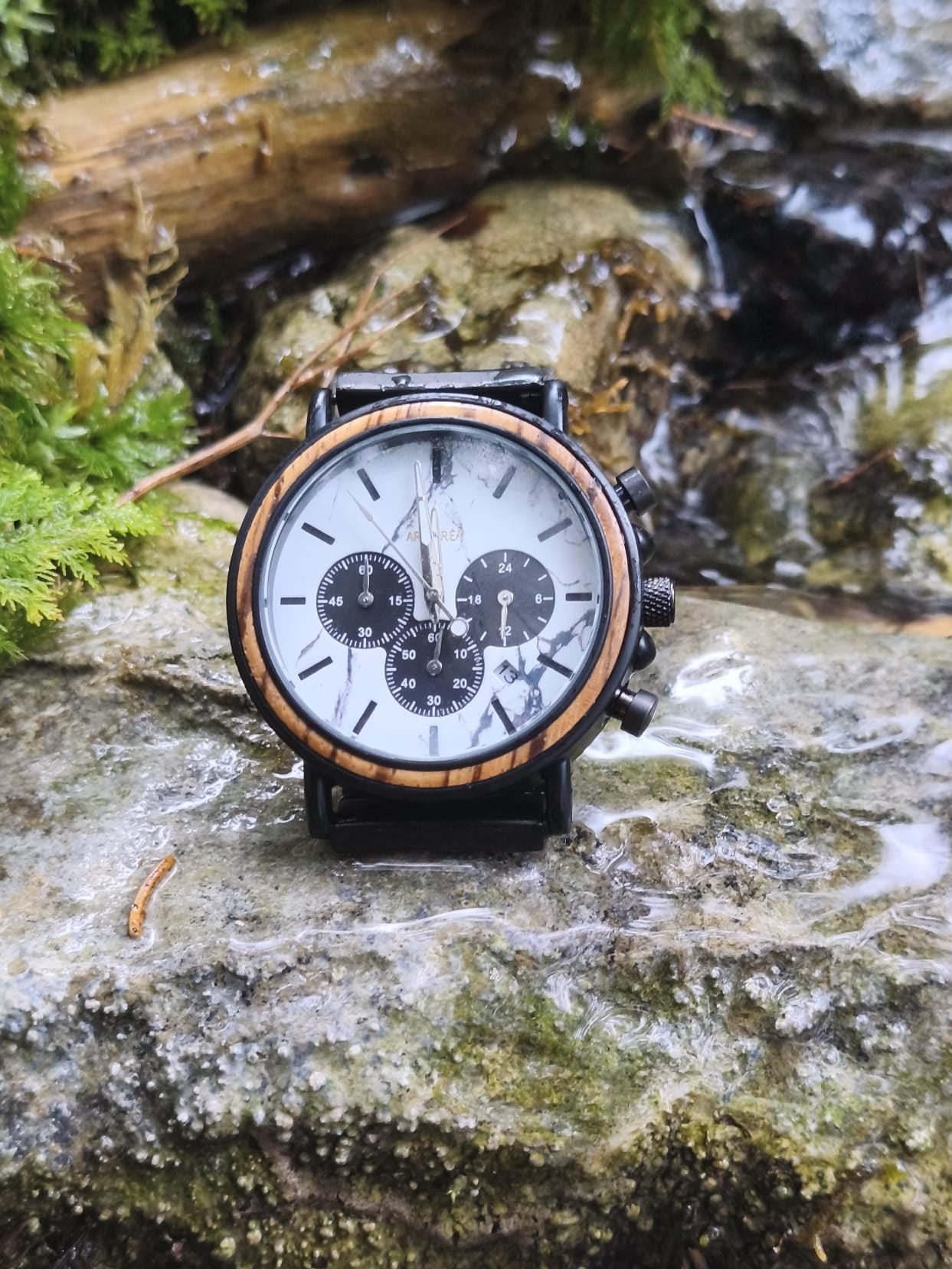 montre en bois sur une pierre qui est sur une rivière en pleine nature